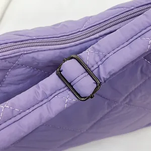 Close-up detail of the adjustable metal buckle and quilted stitching on a purple nylon bag.