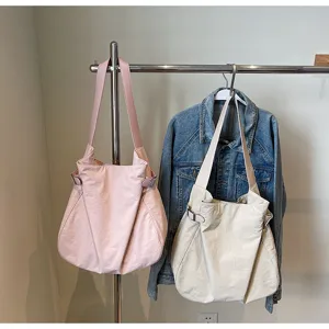 Detailed view of minimalist nylon shoulder tote bags in pink and beige, casual everyday style.