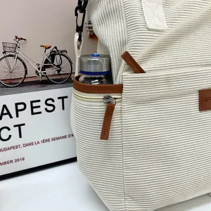 Corduroy tote bag detail showing soft ribbed fabric texture, brown leather trim, and side pocket.