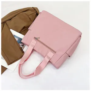 Pink nylon tote bag detail view showing spacious capacity, durable handles and front zip pocket.