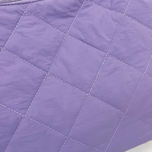 Close up detail view of the purple quilted nylon bag featuring soft texture and zipper.