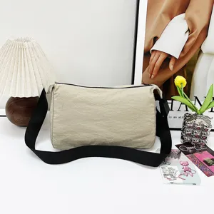 Casual minimalist beige crossbody bag with wide black shoulder strap for daily commute.