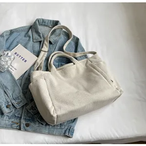 Detailed view of the casual beige corduroy tote bag styled with denim jacket and props.