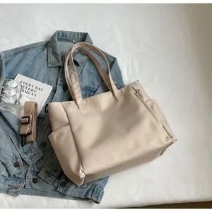 Detailed view of the beige waterproof nylon tote bag showing side pockets, dual straps and texture.