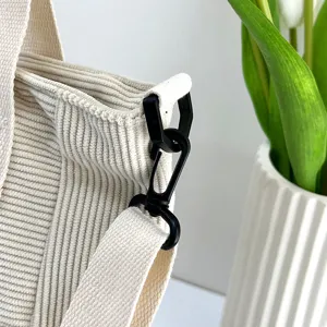 Detailed view of beige corduroy shoulder bag strap hook, casual fashion tote handbag.