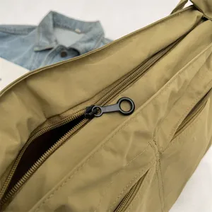Primo piano della borsa a tracolla in nylon kaki, cerniera liscia e tessuto impermeabile.