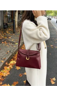 Minimalist burgundy leather shoulder bag for women, elegant envelope crossbody bag with metal buckle.