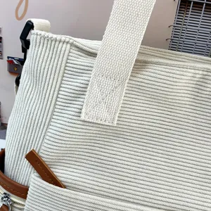 White corduroy tote bag detail view, casual student shoulder bag with wide strap.