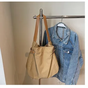 Detailed view of simple lightweight nylon shoulder tote bag in khaki with brown leather straps.