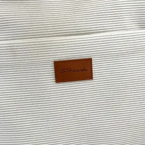 Corduroy tote bag detail close-up showing soft fabric texture and leather brand patch.
