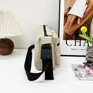 Casual minimalist beige shoulder bag detail, featuring wide black strap and durable zipper.
