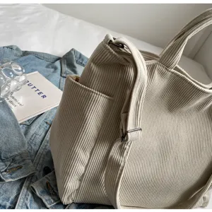 Beige corduroy tote bag with shoulder strap and side pocket, stylish and spacious design.