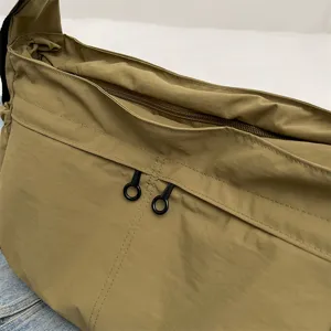 Dettaglio ravvicinato della cerniera e della tasca della borsa a tracolla in nylon.