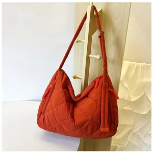 Detailed view of orange quilted nylon hobo bag showing soft texture and modern strap design.