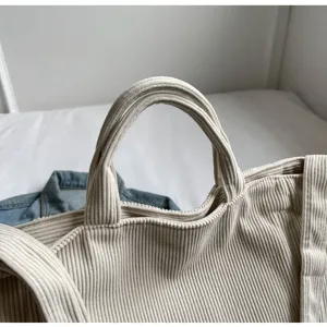 Close-up detail of beige corduroy tote bag handle, soft fabric texture, casual daily style.
