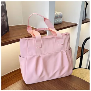 Pink nylon tote bag detail view, highlighting large capacity and side pockets for daily use.