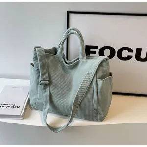 Detail view of light green corduroy tote bag with shoulder strap and spacious pocket design.