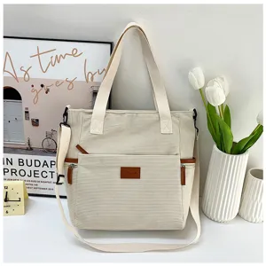 Detailed shot of beige corduroy tote bag with front pocket, shoulder strap, and floral decor.