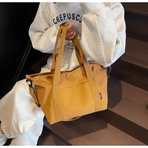 Detailopname van grote gele canvas tote tas met schouderband op de houten trap gefotografeerd.