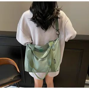 Gedetailleerd overzicht van een grote canvas shopper gedragen als crossbody, effen stijl.