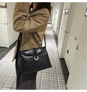 Black soft leather shoulder bag detail, horseshoe metal clasp, elegant daily commuter style.