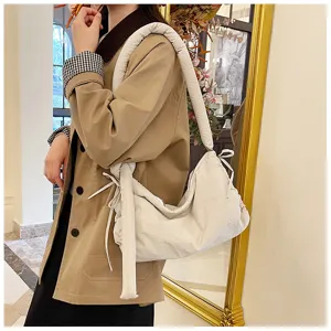 Detailed shot of the soft quilted shoulder bag featuring elegant side tie bow accents.