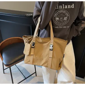 Detail view of khaki canvas tote bag with shoulder straps, buckle details and small pouch.