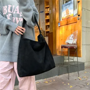 Detailed view of large black suede tote bag, slouchy hobo style for casual daily commute wear.