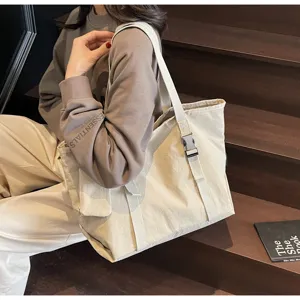 Casual beige canvas tote bag detail shot showing buckle strap and large capacity design.
