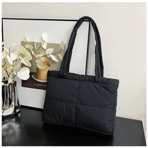 Detailed view of a stylish black quilted nylon tote bag displayed on a dark surface.