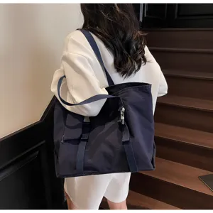 Detailed view of the large capacity dark blue tote bag worn by a model on stairs.