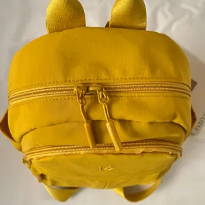 Yellow nylon small backpack with cute bunny ears, compact casual daily school bag detail shot.