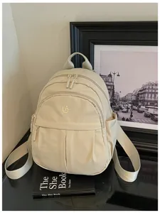 Detail view of beige nylon mini backpack, casual lightweight school bag with front zipper.