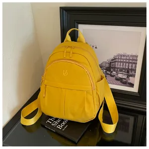Detailed closeup of bright yellow nylon mini backpack, featuring multi-pocket structure.