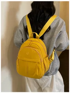 Yellow nylon casual small backpack detail view showing front zippered pocket and straps.