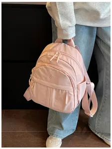 Detailed view of pink casual nylon backpack featuring front zip pocket and dual straps.