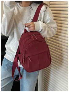 Burgundy nylon mini backpack detail shot, casual daily style, compact size with zipper pocket.
