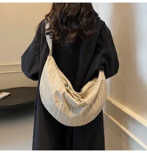 Dettaglio della borsa a tracolla minimalista pieghettata in stile dumpling color beige chic.