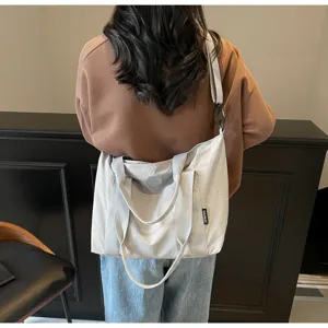Gedetailleerde achterkant van een minimalistische grijze canvas tote bag met schouderband.