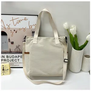 White corduroy tote bag detail showing texture, strap, and spacious pocket design.