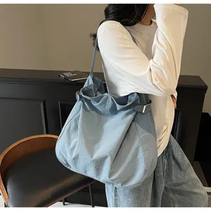 Detailed shot of casual blue nylon shoulder tote bag worn by model, daily commute.