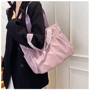 Close-up view of a large capacity pink nylon tote bag with purple straps, ideal for commuting.