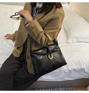 Details of the black soft leather shoulder bag with chic horseshoe metal buckle and strap.