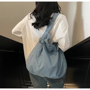 Detail view of casual nylon shoulder bag, slouchy tote design with adjustable buckle on strap.