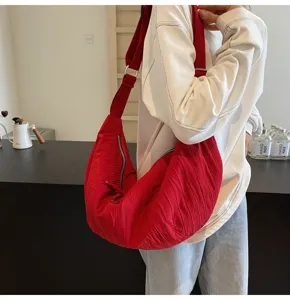 Primo piano dettagliato di una borsa a tracolla morbida e plissé rossa indossata.