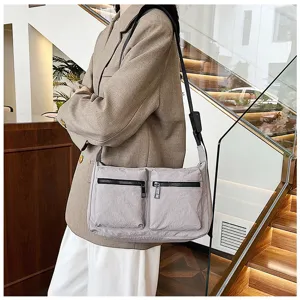 Detail view of a minimalist grey nylon shoulder bag featuring dual front zipper pockets.