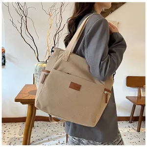 Detailed shot of a beige corduroy tote bag worn on shoulder, large capacity design.