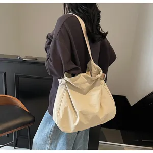 Detail view of a casual minimalist nylon shoulder bag worn on shoulder, soft slouchy texture.