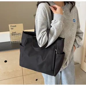 Detailed view of large capacity black nylon tote bag with side pockets and sturdy straps.