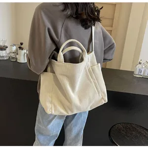 Detail view of a large capacity beige corduroy tote bag with shoulder strap and handles.
